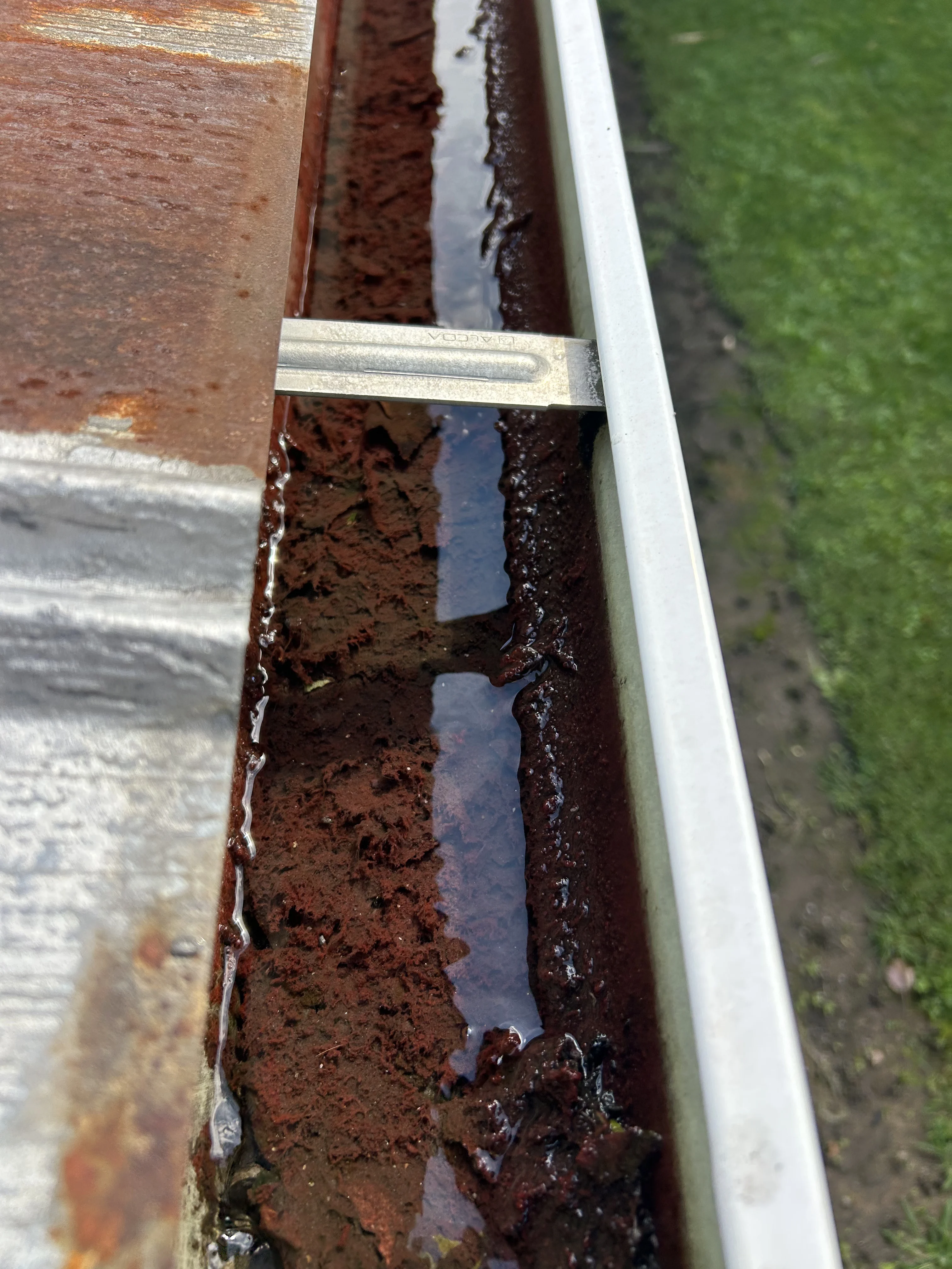 Commercial roof gutter clogged with compacted sediment and debris before cleaning by YZ Construction